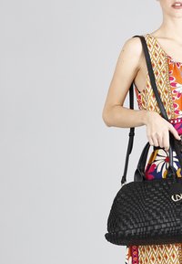 Borsa a tracolla nera intrecciata con doppi manici e tracolla staccabile. Presenta una finitura testurizzata e un accento del logo in tonalità oro sul davanti.