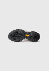 Schwarz-graue Gummisohle mit einem strukturierten Muster, das ein ausgeprägtes hexagonales Grip-Design und einen gelben Akzent in der Mitte aufweist.