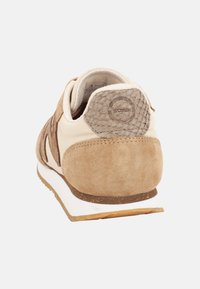 Sneaker beige e marrone chiaro con una parte superiore in suede e pelle, copertura del tallone testurizzata e intersuola bianca. Presenta un logo sul tallone.