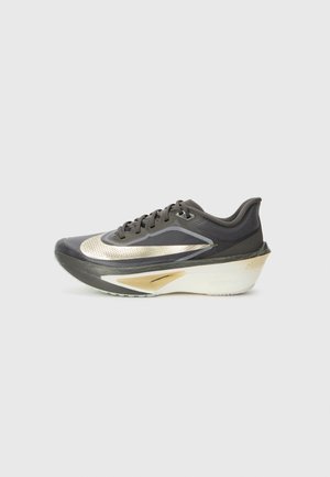 Scarpa da corsa con tomaia in rete nera e accenti dorati metallici; presenta un'ampia intersuola bianca e una suola nera testurizzata per una migliore aderenza.