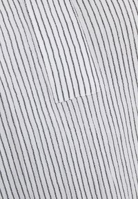 White fabric with thin black vertical stripes, featuring a patch pocket. The texture appears soft and slightly textured.