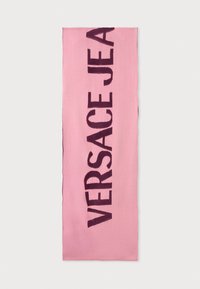 Roza tkanina šal z izrazitim temno vijoličnim besedilom "VERSACE JEAN". Gladka tekstura z čistimi robovi, pravokotna oblika in brez dodatnih okraskov.