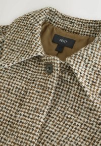 Cappotto a motivo houndstooth marrone e crema con colletto, caratterizzato da un singolo bottone e un rivestimento marrone liscio. Etichetta del marchio visibile.
