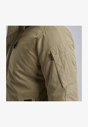 Tan geïsoleerde jas met een rits aan de voorkant, een capuchon met trekkoord en een patchzak op de mouw met een logosticker.