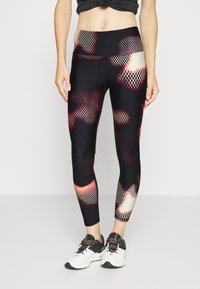 Czarne legginsy z geometrycznym wzorem w czerwonym i kremowym kolorze. Posiadają wysoką talię i dopasowany krój. Materiał wydaje się elastyczny.