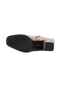 Scarpa in pelle beige con punta arrotondata, dotata di suola in gomma nera e un motivo di grip testurizzato. Include due accenti neri sulla parte superiore.