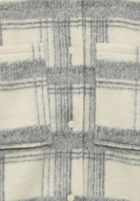 Geruite fleece shirt in crème en grijs, met grote borstzakken, knoopsluiting en een zachte, gestructureerde stof met een geruit patroon.