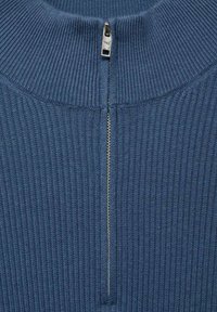 Rebrasti modri pulover z ovratnikom na četrtino z srebrnim zadrgo. Tekstuirana tkanina po celotni površini.