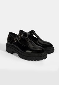 Zwarte gepatineerde leren schoenen met een dikke, gestructureerde zool, met een T-riem ontwerp, studs en een verstelbare gespsluiting.