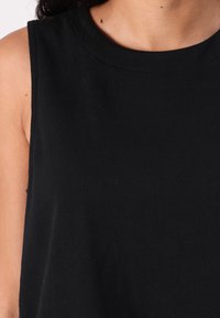 Black sleeveless top made of soft cotton, featuring a round neckline and simple design, with visible stitching and a smooth texture.