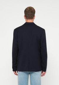 Blazer blu navy realizzato in tessuto morbido, con colletto a punta, maniche lunghe e una fessura singola sul retro. Design minimalista, senza motivi visibili.