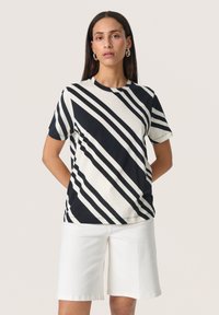 Sort-hvid stribet bomulds t-shirt med korte �ærmer, rund halsudskæring og en let løs pasform, der er parret med hvide shorts.