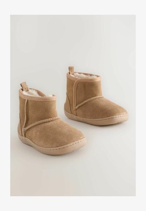 Bottes de cheville en daim tan avec doublure en fausse fourrure, panneaux latéraux élastiques et coutures sur une semelle en caoutchouc profilée. Design compact.