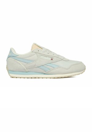 Zapatilla Reebok blanca y azul claro con superposiciones de ante, cierre de cordones y una pequeña bandera del Reino Unido en el panel lateral.