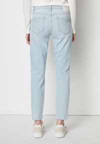 Světle modré džíny rovného střihu vyrobené z denimu, s dvěma zadními kapsami a jednoduchým pasem, kombinované s bílými teniskami.