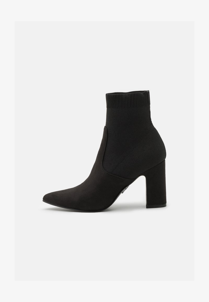 Bottines noires avec un dessus en tricot flexible, un bout pointu et un talon carré, présentant une texture douce semblable à du suède.