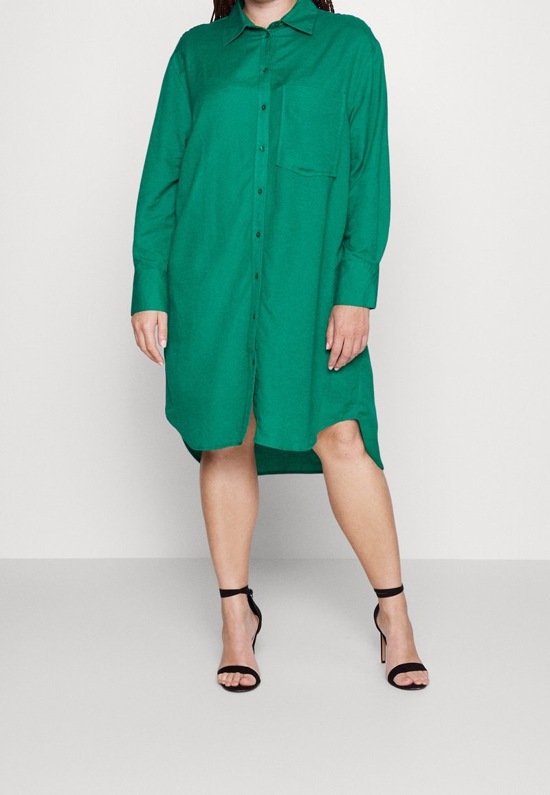 Grön knäppning klänning skjorta med långa ärmar, krage och bröstficka; tillverkad av lättviktsmaterial, har en rundad nederkant och sidoklyftor.