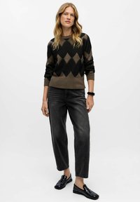 Sort og brun mønstret striktrøje med diamantformer, parret med højtaljede mørke jeans og sorte loafers. Enkel, struktureret design.