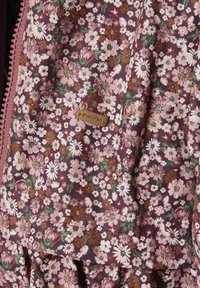 Stoff mit floralem Muster in den Farbtönen Rosa, Grün und Braun; zeigt kleine Gänseblümchen und andere Blumen; beinhaltet ein Markenetikett.
