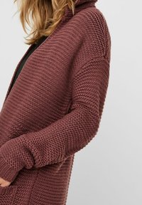 Dzianinowy kardigan w głębokim burgundzie, z fakturowanym wzorem, otwartym przodem i długimi rękawami z prążkowanymi mankietami.