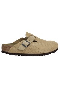 Sabot en daim beige avec design perforé, sangle réglable et semelle en liège ; semelle en caoutchouc avec motif texturé pour une meilleure adhérence.
