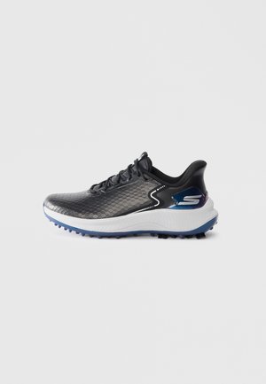 Chaussures de sport noires et argentées avec un dessus texturé, une semelle intermédiaire blanche et une semelle extérieure bleue. Présente un logo sur le côté.