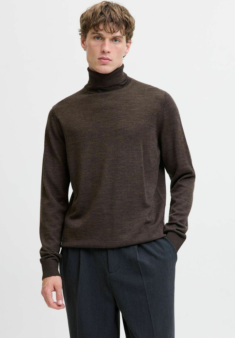 Brauns turtlenecks džemperis, izgatavots no mīksta adījuma materiāla, pieguļošs dizains, garas piedurknes un ribotas aproces. Apvienots ar pelēkiem biksēm.