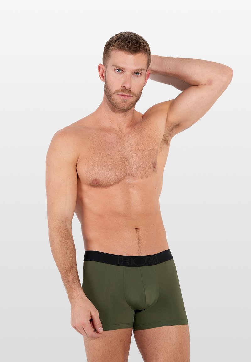 Olive green boxer briefs with a black elastic waistband featuring the brand logo. The fabric has a smooth texture and fitted design.