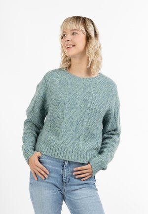 Pulover tricotat de culoare albastră deschisă, cu un model texturat, decolteu rotund și tiv ondulat. Purtați cu blugi cu talie înaltă.