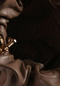 Borsa a mano in pelle marrone chiaro con texture arricciata e dettagli in metallo color oro, con fodera interna scura decorata.