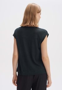 Top corto nero a maniche corte in tessuto leggero, con scollatura rotonda, vestibilità comoda e dettagli di cucitura discreti sulla schiena.