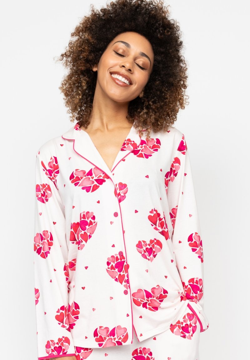Witte pyjama set met roze hartpatronen en kleine rode harten. Langsleeve-top met een kraag, knopen en een ontspannen pasvorm.