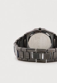 Stylische schwarze Edelstahluhr mit rechteckigem Zifferblatt, quadratischen Gliedern und einem glatten Armband; mit einem polierten silbernen Rückendetail.