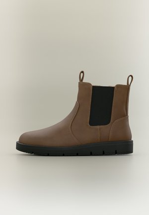 Cizmă Chelsea din piele maro cu panou elastic negru lateral, cârlige de tragere la gleznă și talpă de cauciuc neagră pe un fundal simplu și luminos.