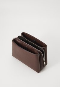 Pochette in pelle marrone con zip, dotata di due scomparti, superficie liscia, bordi arrotondati e dettagli in metallo argentato.