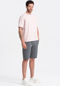 Lyselilla bomulds T-shirt, grå shorts og hvide sneakers. Løs pasform; simpelt design uden mønstre. Ren og minimalistisk stil.