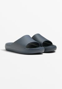 Donkergrijze rubberen slidersandalen met een open teen ontwerp, gestructureerde bovenkant en flexibele zool met een patroon voor grip en traction.