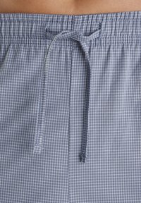 Detailný záber na modro-biele kockované šnúrkové pásky z ľahkého textilu.