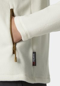 Witte fleece pullover met een ritszak en een Polartec-label; heeft een gladde textuur en een strakke manchet.