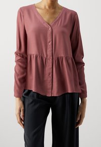 Blusa a maniche lunghe color lampone con scollo a V, davanti con bottoni e vita arricciata, realizzata in un tessuto leggero e morbido.