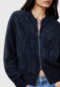 Marineblauer Reißverschluss-Pullover aus weichem, flauschigem Material mit gerippten Bündchen und Saum. Verfügt über einen glänzenden silbernen Reißverschluss und eine lässige Passform.