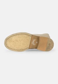 Suela de zapato de ante beige con base de goma texturizada y parche marrón. Firmado con "florina 37" en cursiva, mostrando desgaste en la superficie.