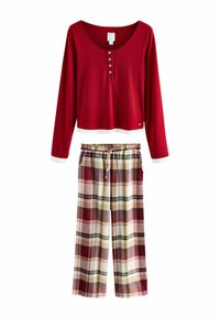 Red long-sleeve top with button placket and white trim, paired with plaid wide-leg pants in cream, burgundy, and green tones.