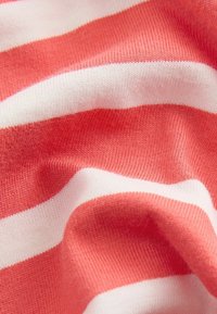 Tissu rayé corail et blanc avec une texture douce, comportant des rayures horizontales alternées et de douces ondulations.