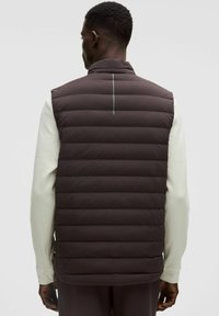 Gilet imbottito marrone scuro con colletto alto, caratterizzato da sezioni a coste orizzontali, una striscia verticale riflettente e una texture liscia e elegante.