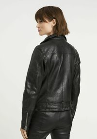Czarna skórzana kurtka o dopasowanym kroju, z zapięciem na suwak z przodu i zamkami na mankietach. Gładka struktura, minimalne przeszycia i klasyczny kołnierz.