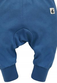 Blauwe katoenen babybroek met ribbelmanchetten, een ronde achterpaneel en een klein zeilbootlogo in de bovenhoek. Zachte textuur.