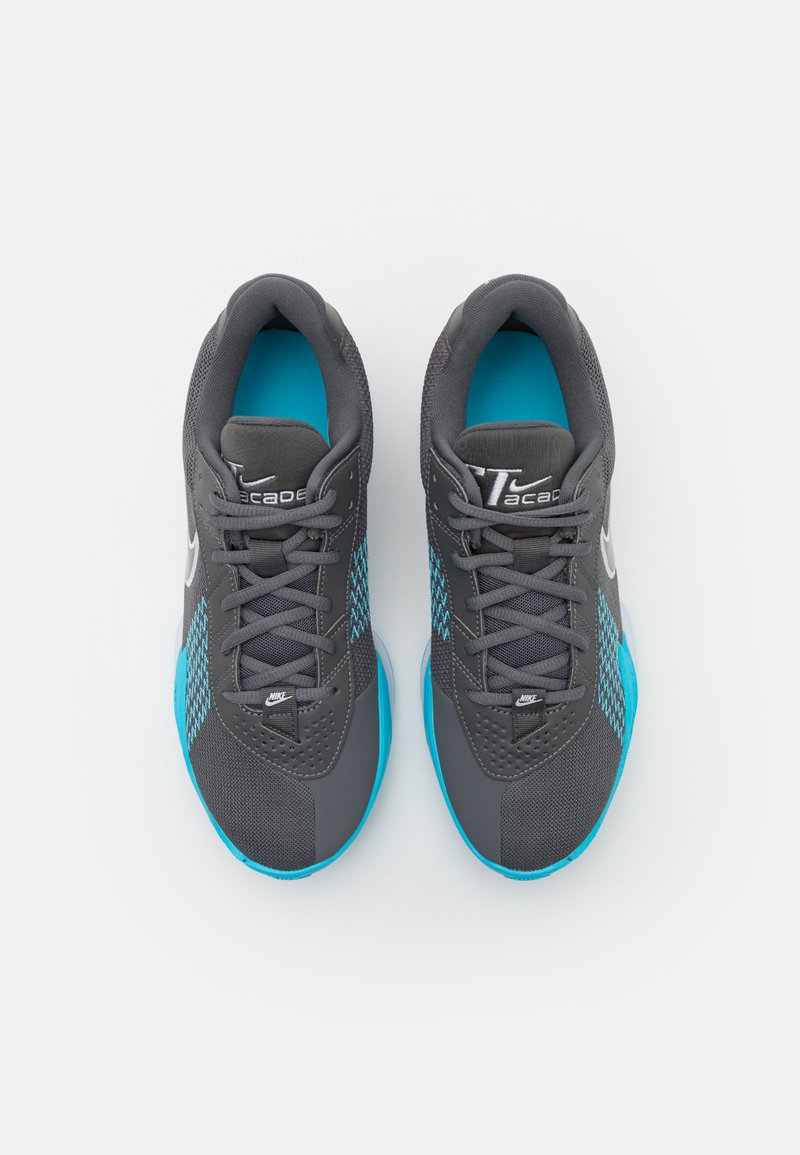 Zapatillas deportivas grises con acentos azules, parte superior de malla y sintético, punta redonda, diseño texturizado y suela en contraste.