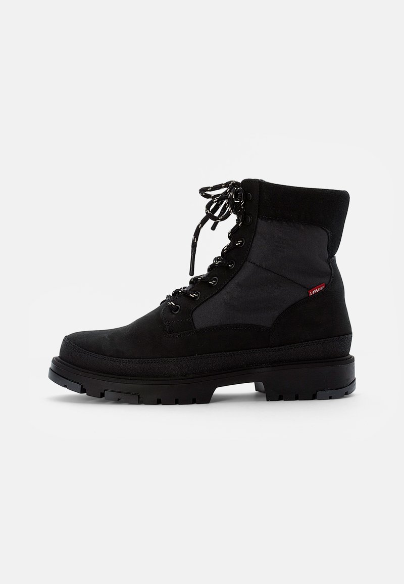 Bota negra de ante y textil con cordones, que presenta un cuello acolchado, suela de goma gruesa y texturas contrastantes en la parte superior. Su diseño elegante mejora la durabilidad.