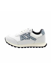 Sneaker atletico bianco con accenti grigi, materiali in rete e scamosciato, punta rotonda, suola ammortizzata e suola esterna in gomma nera testurizzata.